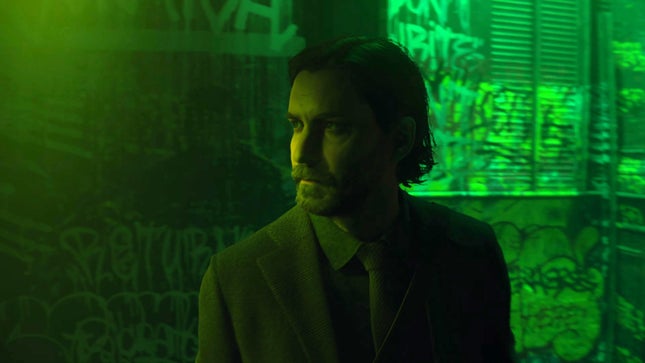 Ein Screenshot von Alan Wake II zeigt Alan Wake, wie er in einer grün beleuchteten Gasse steht. 